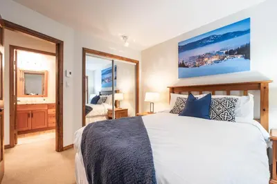 a bedroom with a large white bed with blue pillows at Blackcomb Greens by Outpost Whistler in Whistler