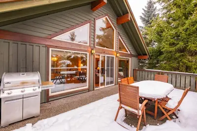 a screened in porch with a table and a stove at Spruce Grove Chalet by Outpost Whistler in Whistler