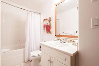 a bathroom with a sink and a toilet and a mirror at Spruce Grove Chalet by Outpost Whistler in Whistler