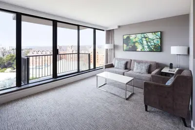 a living room with a couch and a table and windows at DoubleTree by Hilton Hotel & Suites Victoria in Victoria
