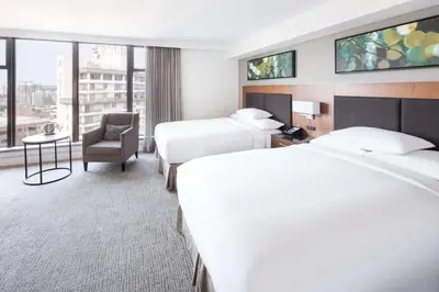 a hotel room with two beds and a chair at DoubleTree by Hilton Hotel & Suites Victoria in Victoria