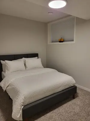a bedroom with a bed with white sheets and a window at Modern 2 Bed Urban Retreat in Calgary
