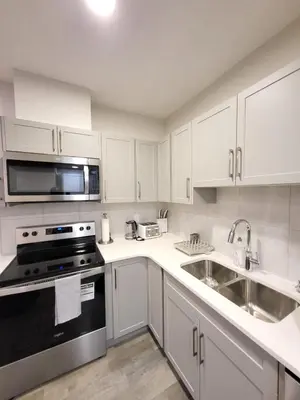 a kitchen with white cabinets and a stove and sink at Modern 2 Bed Urban Retreat in Calgary