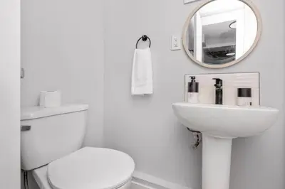 a white bathroom with a toilet and a mirror at CenterStreet-Cozy 2bedroomSuite in Calgary