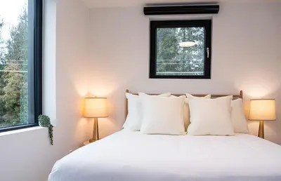 a bedroom with a white bed with two lamps at Powder Pines Retreat by Revelstoke Vacations in Revelstoke