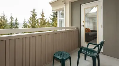two green chairs sitting on a porch with a window at Woodrun Lodge 517 | Large Ski-In Ski-Out Condo by Upper Village w/ Mountain Views & Shared Hot Tub in Whistler