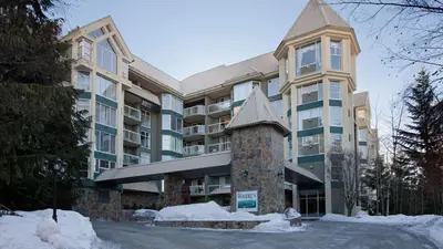 a large apartment building with snow in front of it at Woodrun Lodge 417 | Ski-In Ski-Out, Pool, Hot Tub, Free Parking in Whistler