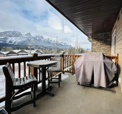 a table and chairs on a balcony with mountains at Canmore Mountain Retreat - Heated Pool & Hot-tub in Canmore