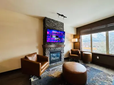 a living room with a fireplace and a flat screen tv at Canmore Mountain Retreat - Heated Pool & Hot-tub in Canmore