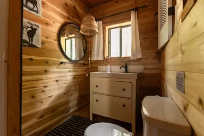 a bathroom with a toilet and a mirror and a sink at Romantic Off-Grid Cabin by Glacier lake in Pemberton
