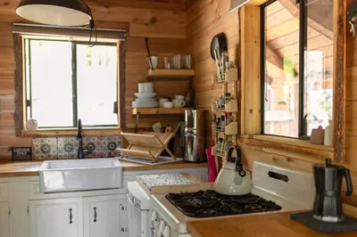 a kitchen with a stove top oven next to a window at Romantic Off-Grid Cabin by Glacier lake in Pemberton