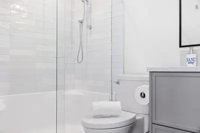 a white bathroom with a shower and a toilet at Seas The Day Saratoga at THE BEACH HOUSE in Campbell River
