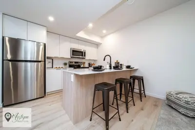 a kitchen with a stainless steel refrigerator and stools at Modern Suite King Bed Near Whyte Ave and U of A WIFI in Edmonton