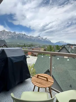 a balcony with a table and chairs and mountains at W400 Mountain Surround Top Floor Canmore Vacation in Canmore