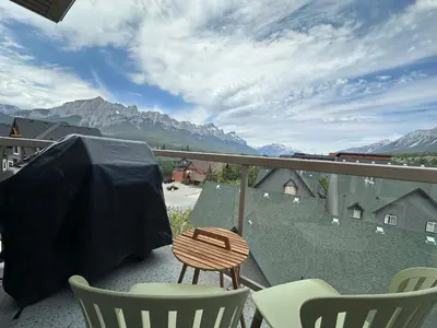 a balcony with a table and chairs and mountains at W400 Mountain Surround Top Floor Canmore Vacation in Canmore