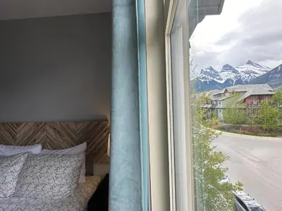 a bedroom with a bed and a window with a mountain view at W400 Mountain Surround Top Floor Canmore Vacation in Canmore