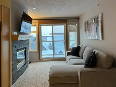 a living room with a couch and a fireplace at W400 Mountain Surround Top Floor Canmore Vacation in Canmore