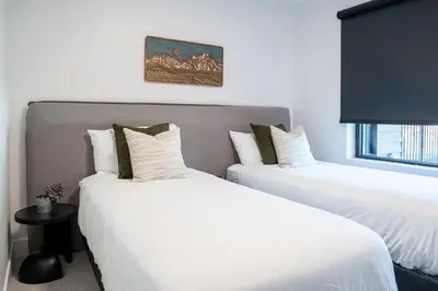 two beds in a room with white sheets at Villa 23 Cabot Peaks by Revelstoke Vacations in Revelstoke