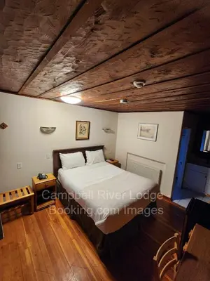 a bedroom with a bed and a wooden ceiling at Campbell River Lodge in Campbell River