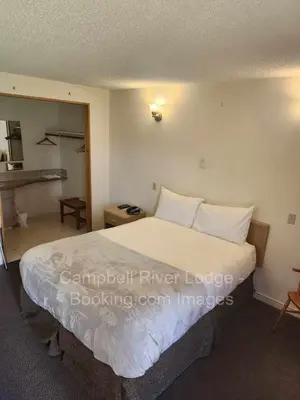 a bedroom with a large bed with white sheets and pillows at Campbell River Lodge in Campbell River