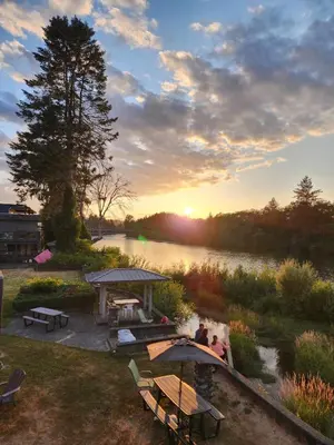 a group of people sitting under umbrellas near a river at Campbell River Lodge in Campbell River