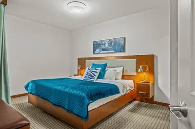 a bedroom with a large bed with a blue blanket at Romantic Mountain Escape - Hot Tubs & Private Balcony! managed by Little Sister Getaways in Canmore