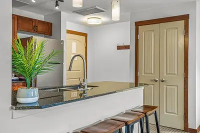 a kitchen with a sink and a counter with stools at Romantic Mountain Escape - Hot Tubs & Private Balcony! managed by Little Sister Getaways in Canmore