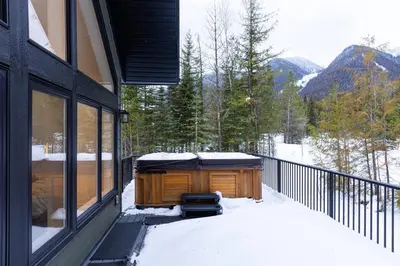 a hot tub on a balcony of a house with snow at Powder House Chalet by Fernie Central Reservations in Fernie