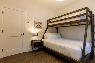 a bedroom with a bunk bed with a lamp and a door at Powder House Chalet by Fernie Central Reservations in Fernie