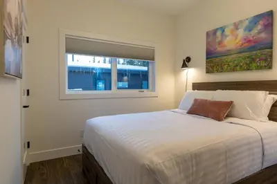 a bedroom with a white bed with a window at Powder House Chalet by Fernie Central Reservations in Fernie