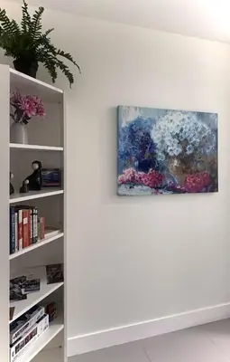 a painting hanging on a wall next to a book shelf at Blissful Stay in Surrey in Surrey