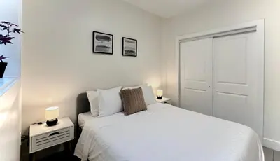 a white bedroom with a bed and two night stands at Blissful Stay in Surrey in Surrey