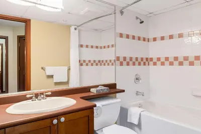 a bathroom with a sink and a toilet and a tub at Cascade Lodge with front desk check in services, ski valet service, boot and glove dryer, 2 hot tubs, year round heated pool, gym, sauna, change rooms & showers, WIFI, cable TV in Whistler