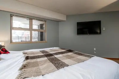 a bedroom with a bed with a checkered blanket on it at Creekside Slopeside 1BR with pool, hot tub, BBQ in Whistler