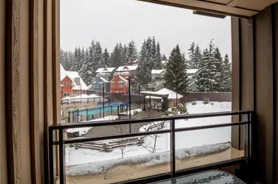 a window with a view of a snow covered yard at Creekside Slopeside 1BR with pool, hot tub, BBQ in Whistler