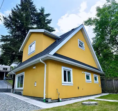 a yellow house with a black roof at Vancouver’s Homey Laneway House in Vancouver