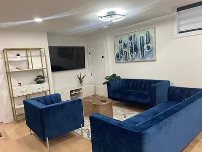 a living room with blue couches and a flat screen tv at Stylish 2 Bedroom suite in SW Edmonton close to Windermere and Edmonton International Airport in Edmonton