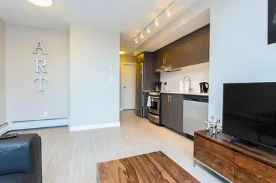 a living room with a television and a kitchen at Hendrix Luxury Apartments by Corporate Stays in Edmonton