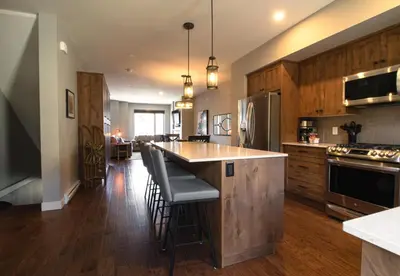 a kitchen with wooden cabinets and a island with bar stools at Echo Landing #20 townhouse in Sun Peaks