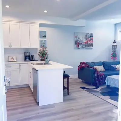 a kitchen with white cabinets and a blue couch at Ground level two bedrooms Suite near Lake and Golf Course in Victoria