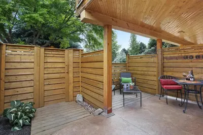 a wooden privacy fence with a table and chairs on a patio at Uncork and Unwind in West Kelowna