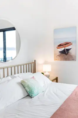 a bedroom with a white bed with a picture of a boat at Beachfront Luxury Suite #19 at THE BEACH HOUSE in Campbell River