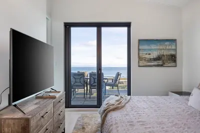 a bedroom with a television and a table with chairs at Beachfront Villa #14 at The Beach House in Campbell River