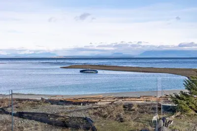 a beach with a boat in the water at Beachfront Villa #14 at The Beach House in Campbell River