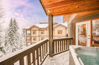 a balcony with a hot tub and snow covered trees at Eagle Ridge Pet-Friendly Chalet in Big White