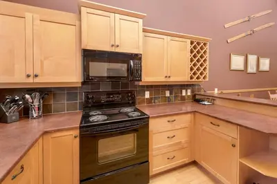 a kitchen with wooden cabinets and a stove top oven at Eagle Ridge Pet-Friendly Chalet in Big White