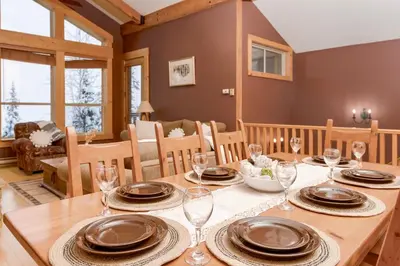 a dining room with a table with plates and wine glasses at Eagle Ridge Pet-Friendly Chalet in Big White