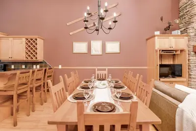 a dining room with a table with chairs and a chandelier at Eagle Ridge Pet-Friendly Chalet in Big White