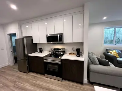 a kitchen with a stove and a couch in a room at Grand Boulevard Basement Suite in North Vancouver