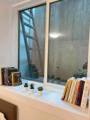 a window with books and plants on a shelf at Grand Boulevard Basement Suite in North Vancouver